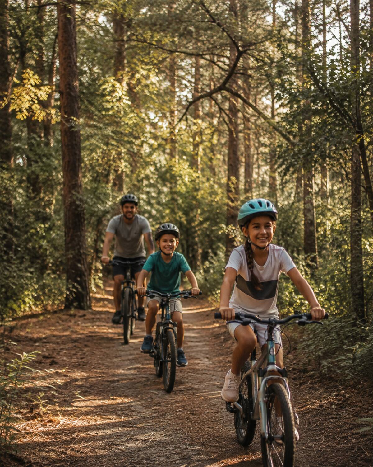 Family biking together along a wooded neighborhood trail